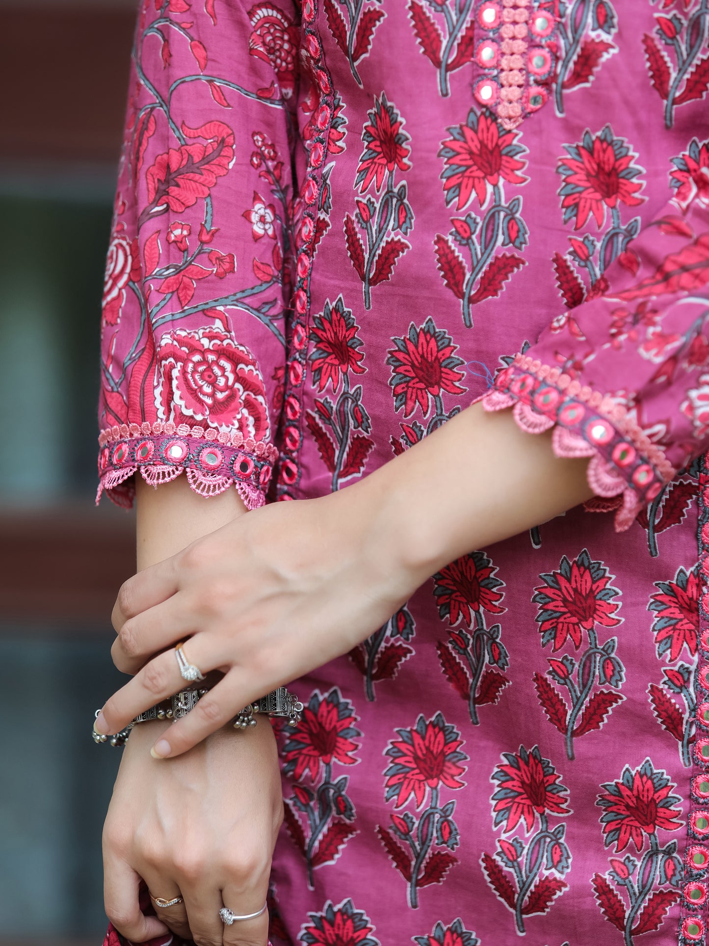 Detailed view of the floral printed 3/4th sleeve with lace work, part of the Dark Fuschia Mirror Work Cotton Suit from Cottons Daily, showcasing the intricate floral patterns and comfortable fit suitable for both casual and formal occasions.