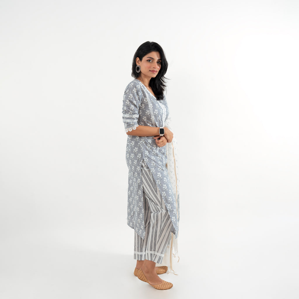 Pant and Dupatta Details: Focus on the white printed straight-fit pants paired with the Chanderi white floral print dupatta featuring a golden border, complementing the kurta in the Floral Grey with Lace Work Striped Pant Cotton Suit by Cottons Daily.