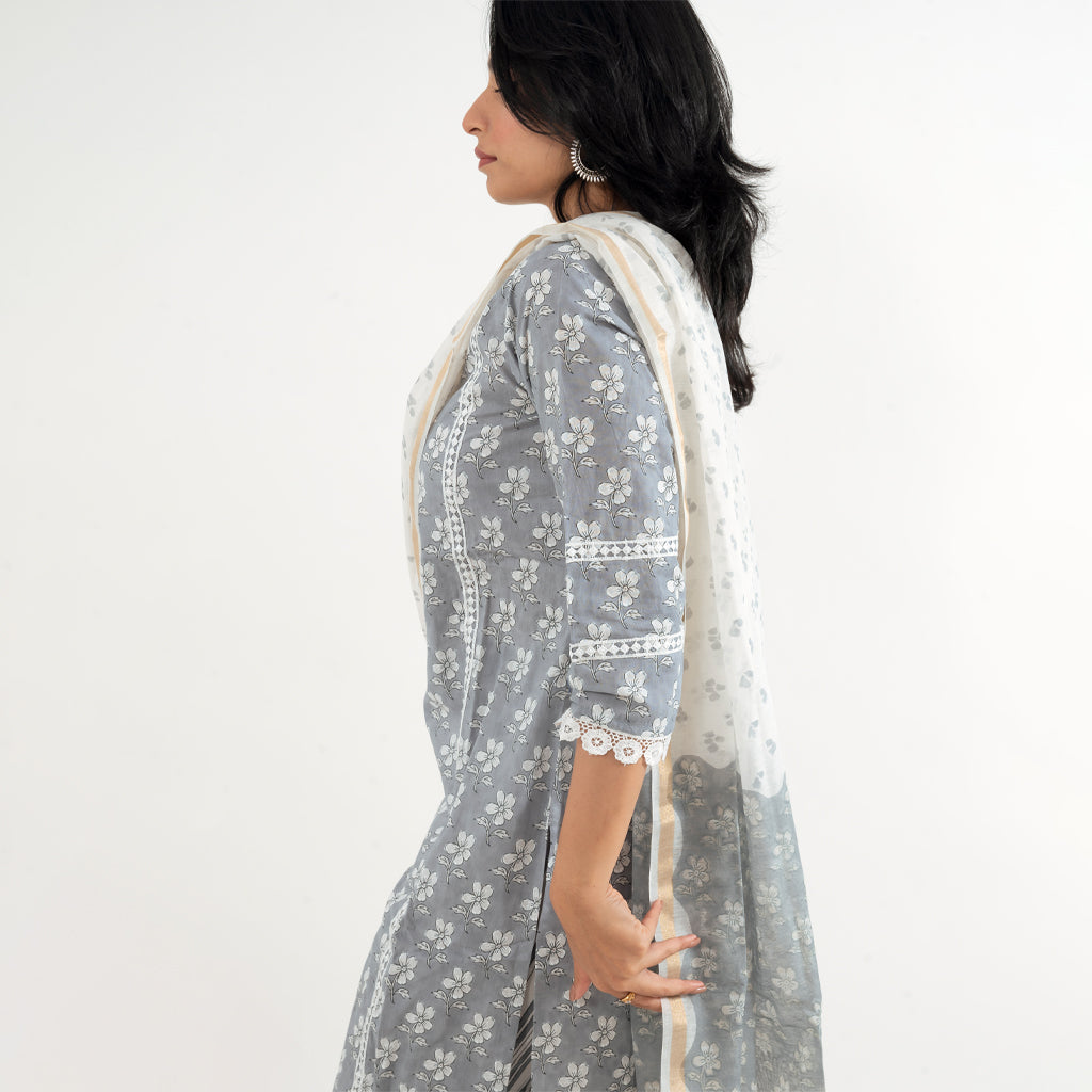 Side View: Side view of the model wearing Cottons Daily's Floral Grey with Lace Work Striped Pant Cotton Suit and highlighting the design on the sleeves.