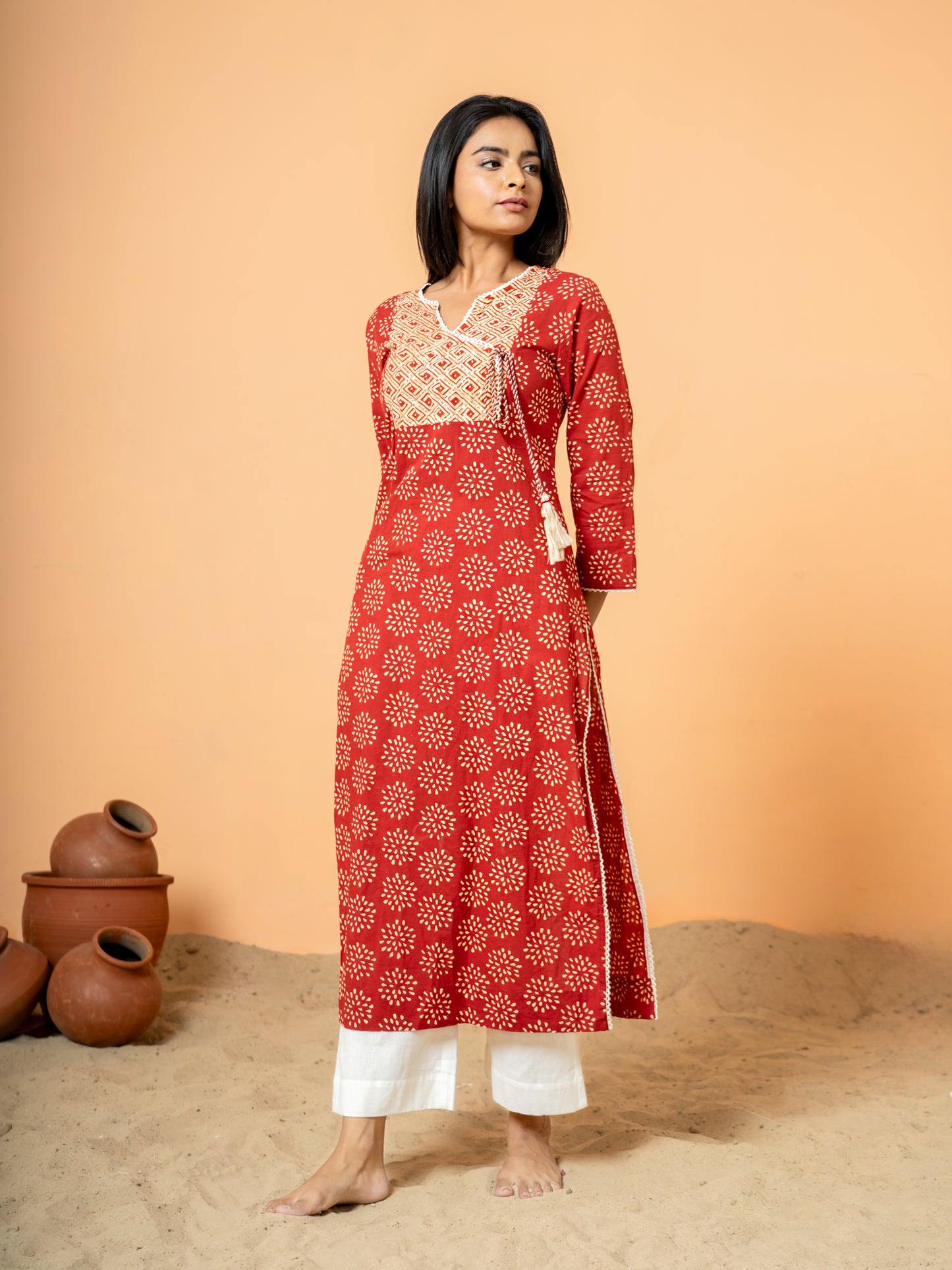Close-up detail of the vibrant red cotton fabric showing the intricate rangoli print design on the kurta.