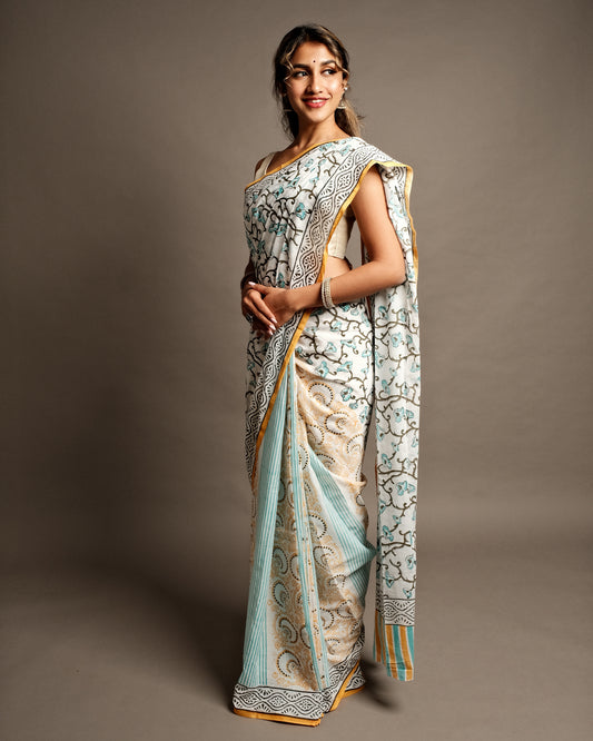 A White Floral Half & Half Handblock Print Mul Cotton Saree, popularly known as malmal cotton saree in Kolkata, West Bengal, featuring a soft and feather-light fabric perfect for summer wear, with elegant curtain creeper prints in blue florals and a matching white blouse with a black border and running print.